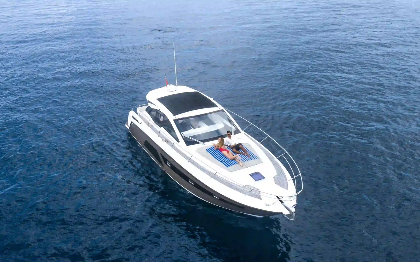 Aerial view of guests relaxing on the bow of a private yacht at sea