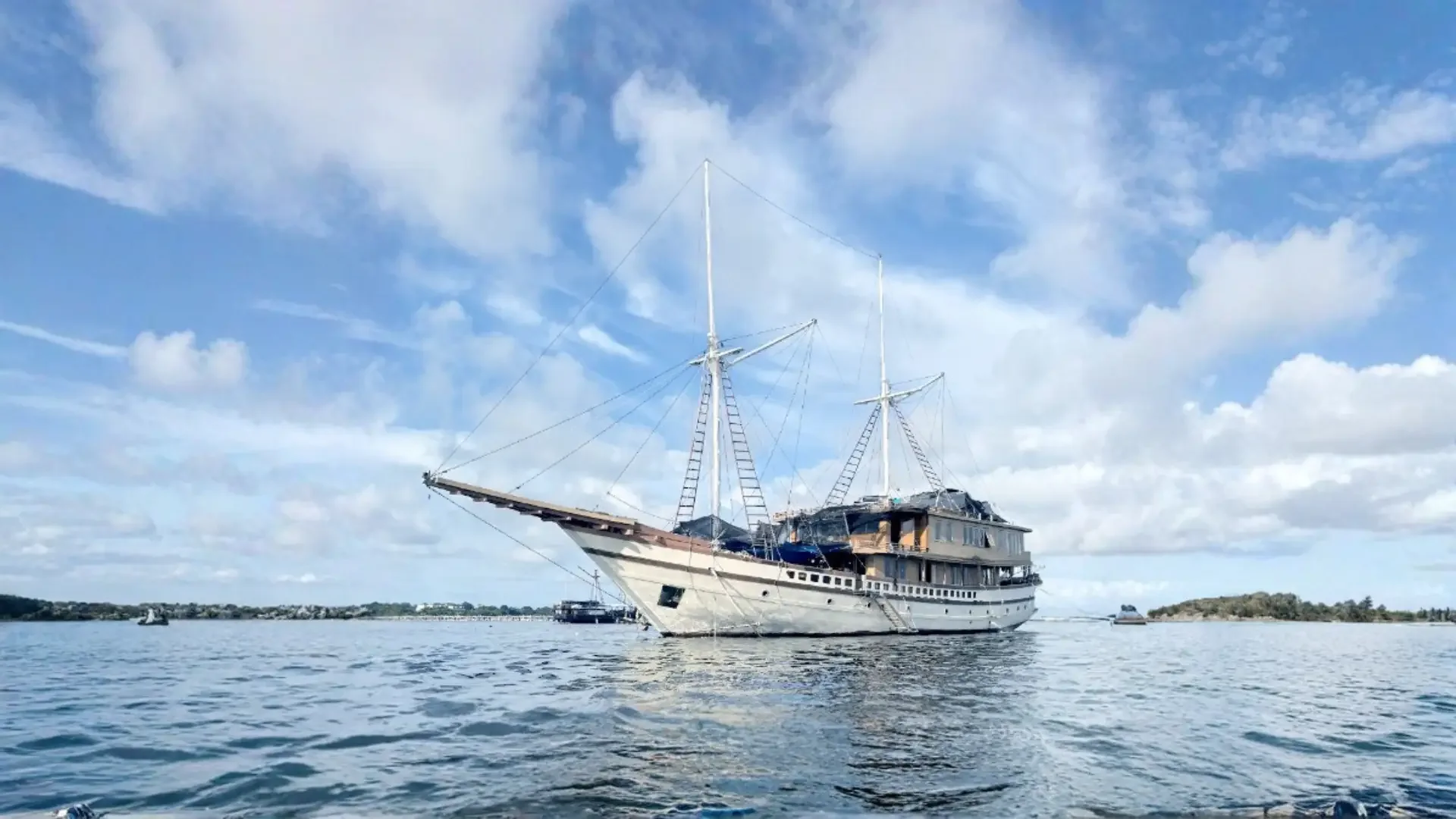 A traditional Phinisi charter vessel lying at anchor in calm water