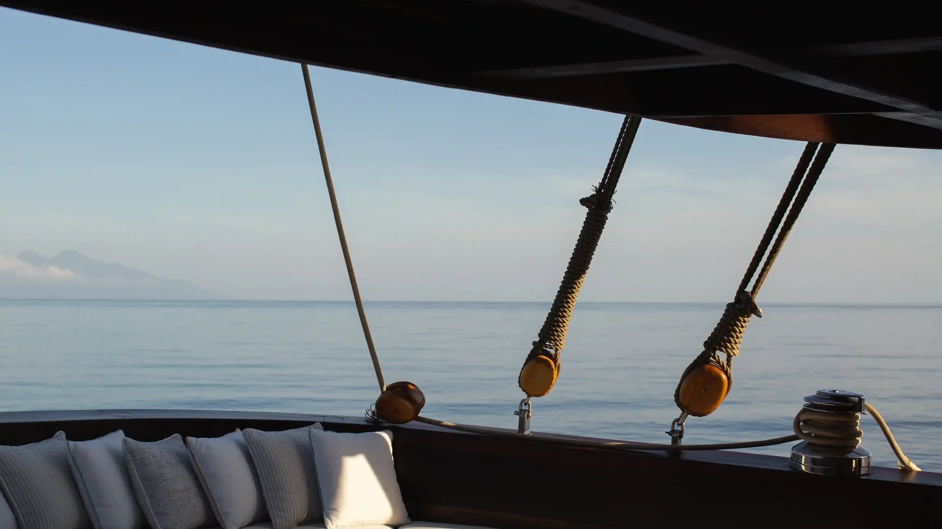 Cushioned seating on the foredeck of a Phinisi charter yacht at sea