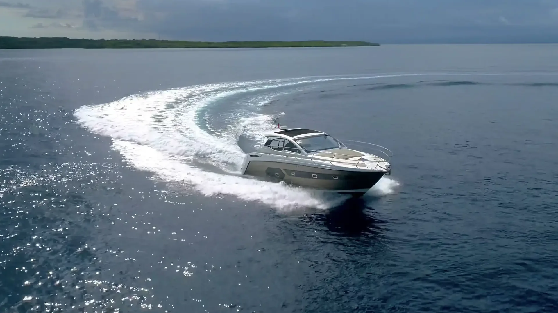 Aerial view of a private motor yacht carving a wake across open water